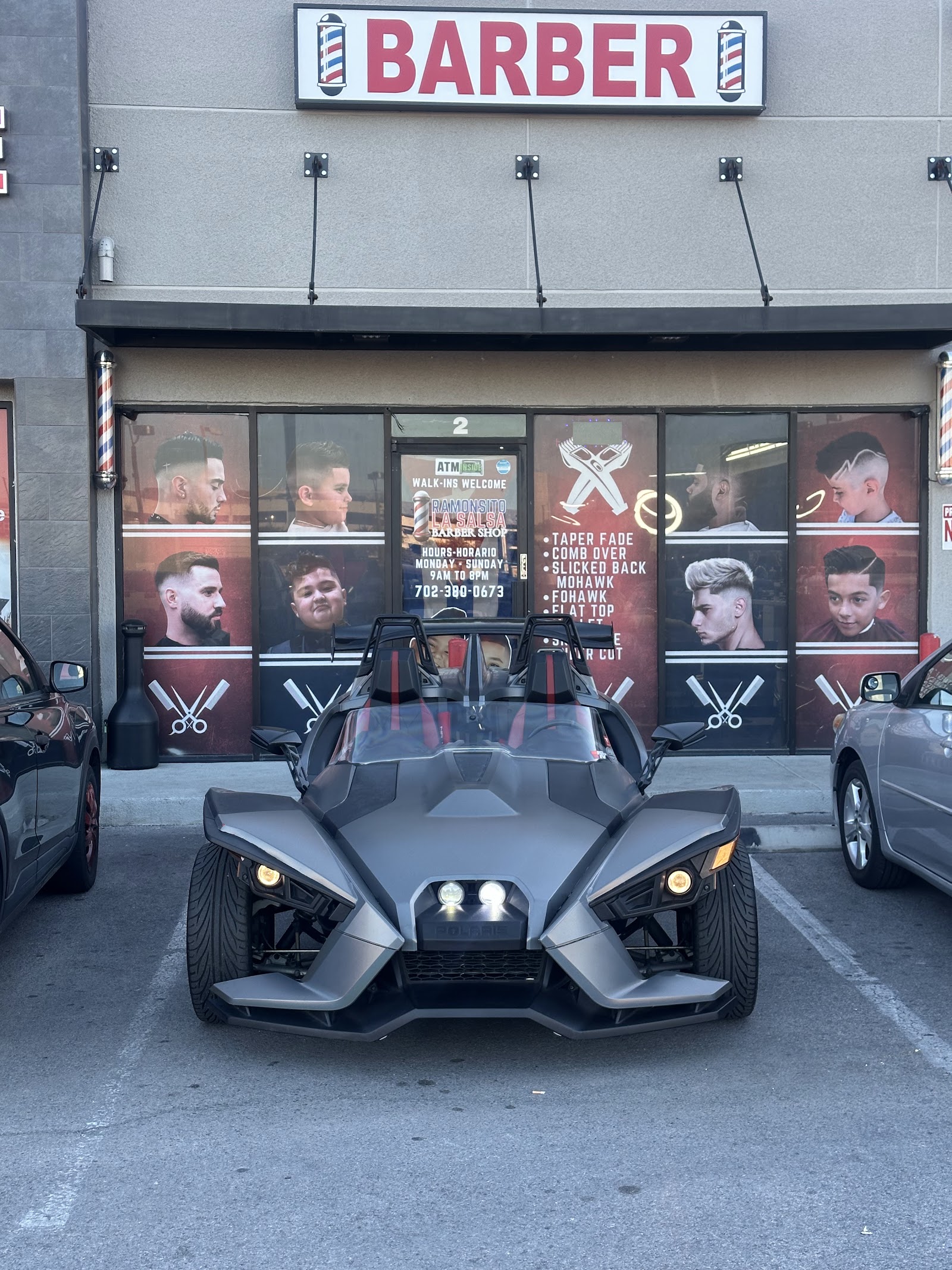 A Polaris Slingshot parked in front of the barber shop storefront