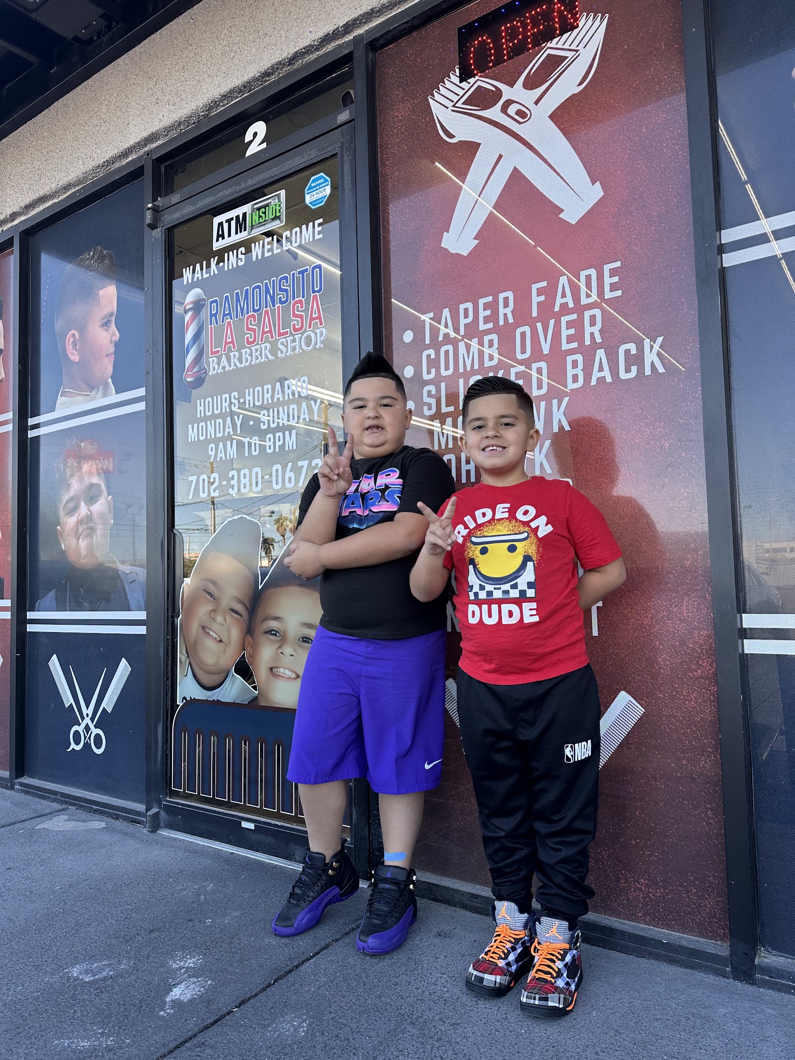 Two young boys posing in front of the barber shop entrance